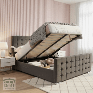 The contemporary Cube ottoman bed in charcoal grey, with its mattress lifted to showcase the deep storage area, highlighting its unique geometric cubed upholstery.